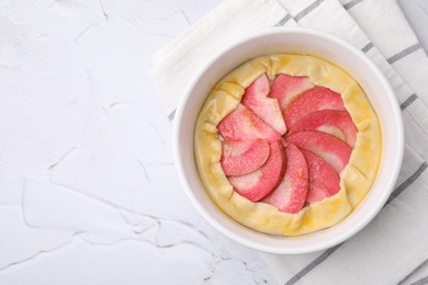 Photo of Baking dish with fresh dough and apples on white textured table, top view with space for text. Making galette