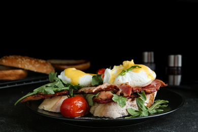 Photo of Delicious eggs Benedict served on black table