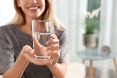 Photo of Woman holding glass with clean water at home, closeup. Space for text