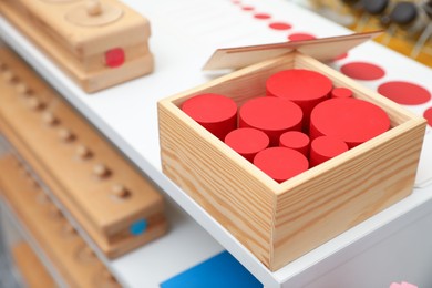 Set of wooden geometrical objects and other montessori toys on shelves, closeup