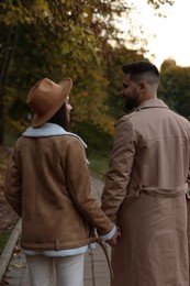 Photo of Happy young couple walking in autumn park, back view