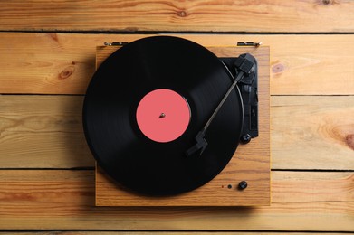 Photo of Modern vinyl record player with disc on wooden background, top view