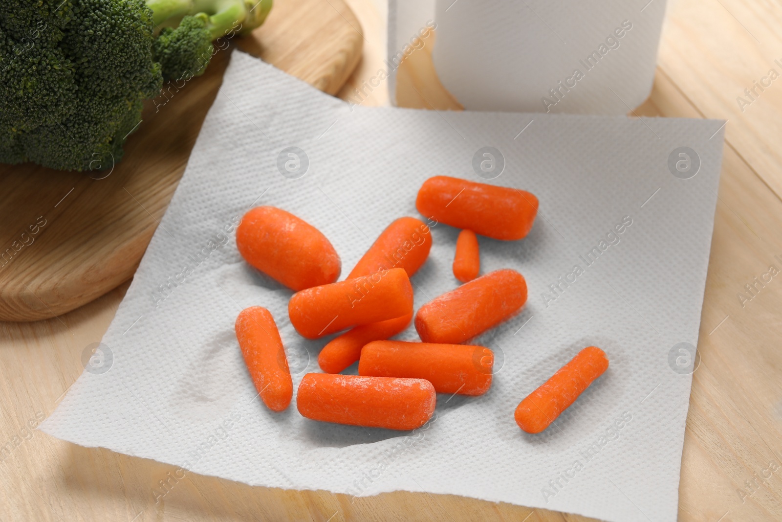 Photo of Carrots drying on paper towel on wooden table, closeup