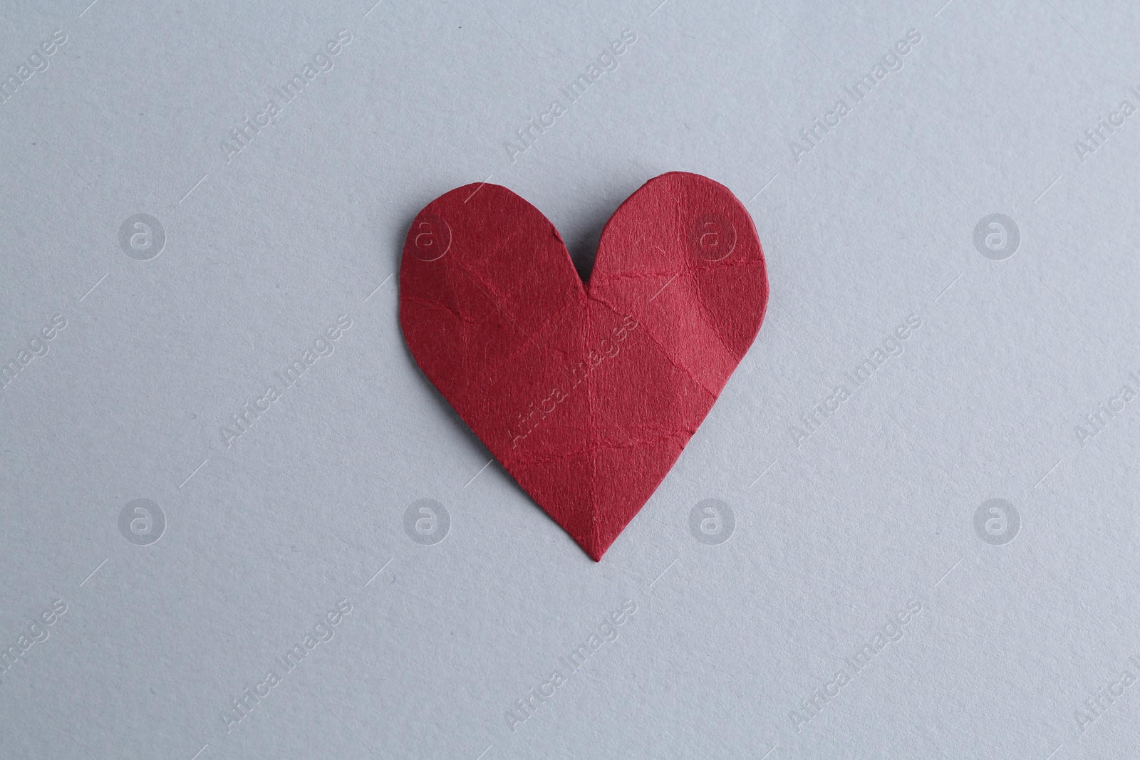 Photo of Red crumpled paper heart on gray background, top view