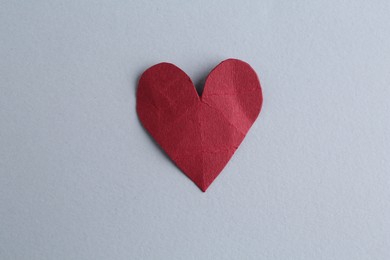 Red crumpled paper heart on gray background, top view