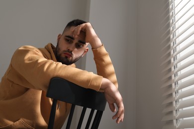 Sad man sitting on chair near window. Space for text