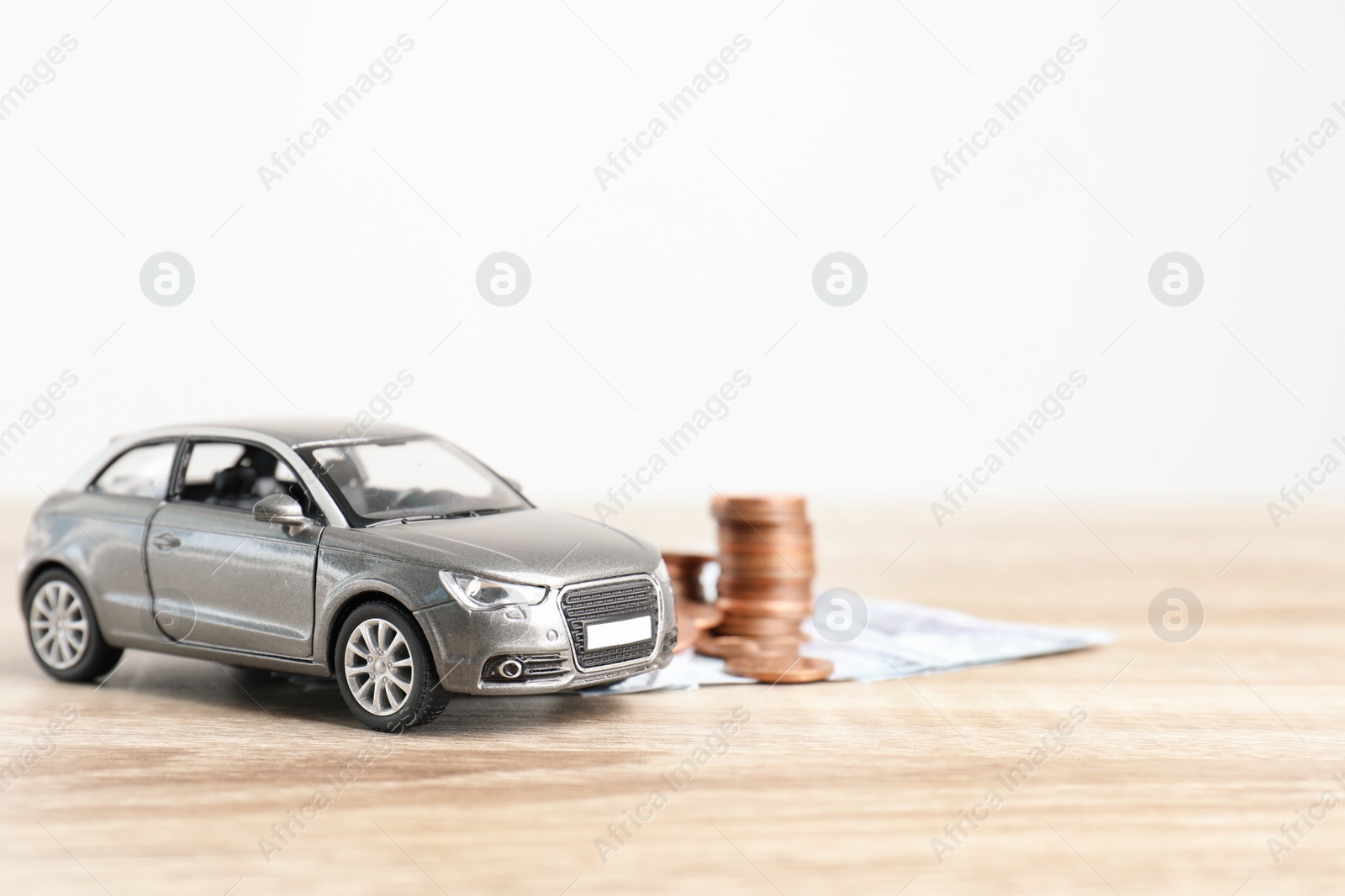 Photo of Toy car and money on table, space for text. Vehicle insurance