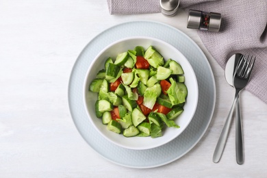 Bowl of vegetarian salad with cucumber, tomato and lettuce served on table, flat lay