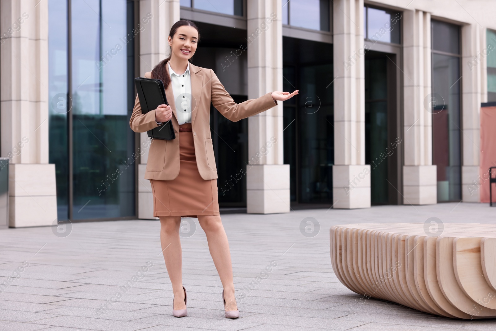 Photo of Female real estate agent with leather portfolio outdoors