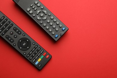 Photo of Remote controls on red background, flat lay. Space for text