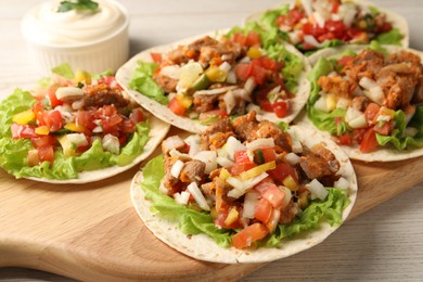 Delicious tacos with vegetables and meat on white wooden table