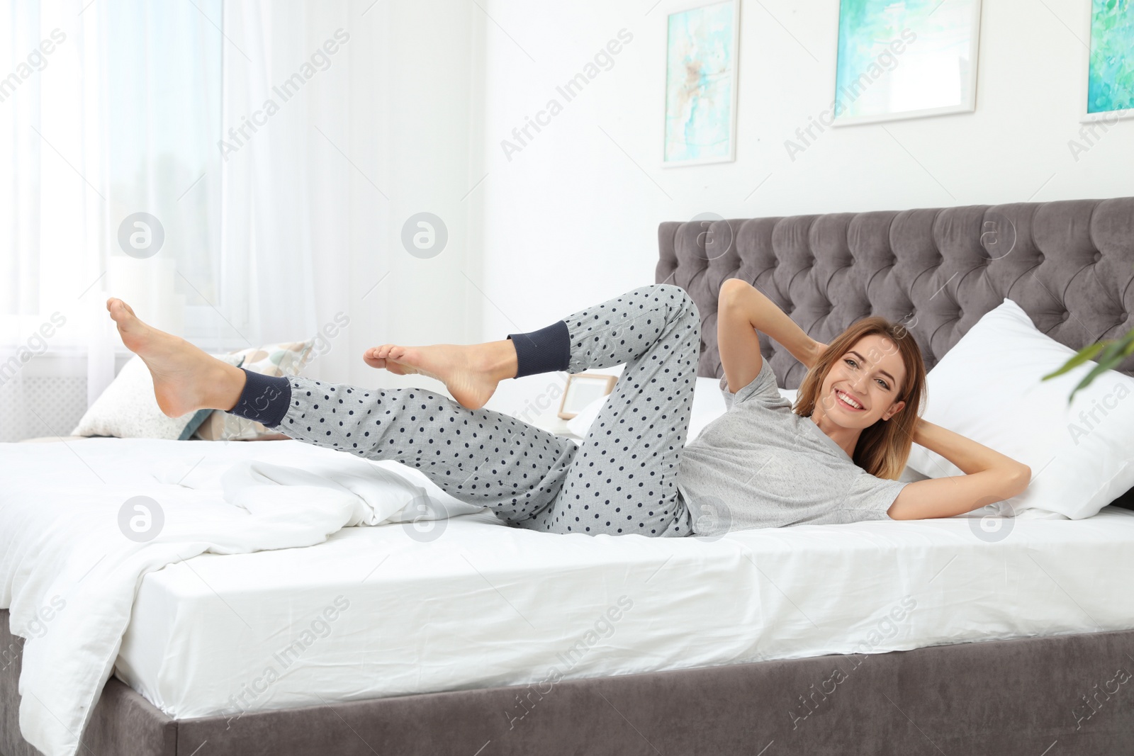 Photo of Young beautiful woman doing exercise on bed at home. Morning fitness