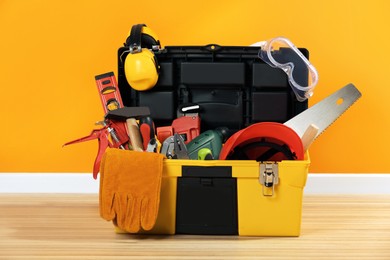 Photo of Box with different tools for repair on floor near orange wall