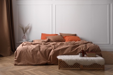 Photo of Bed with orange and brown linens in stylish room