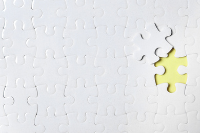Photo of Blank white puzzle with separated piece on yellow background, top view. Space for text