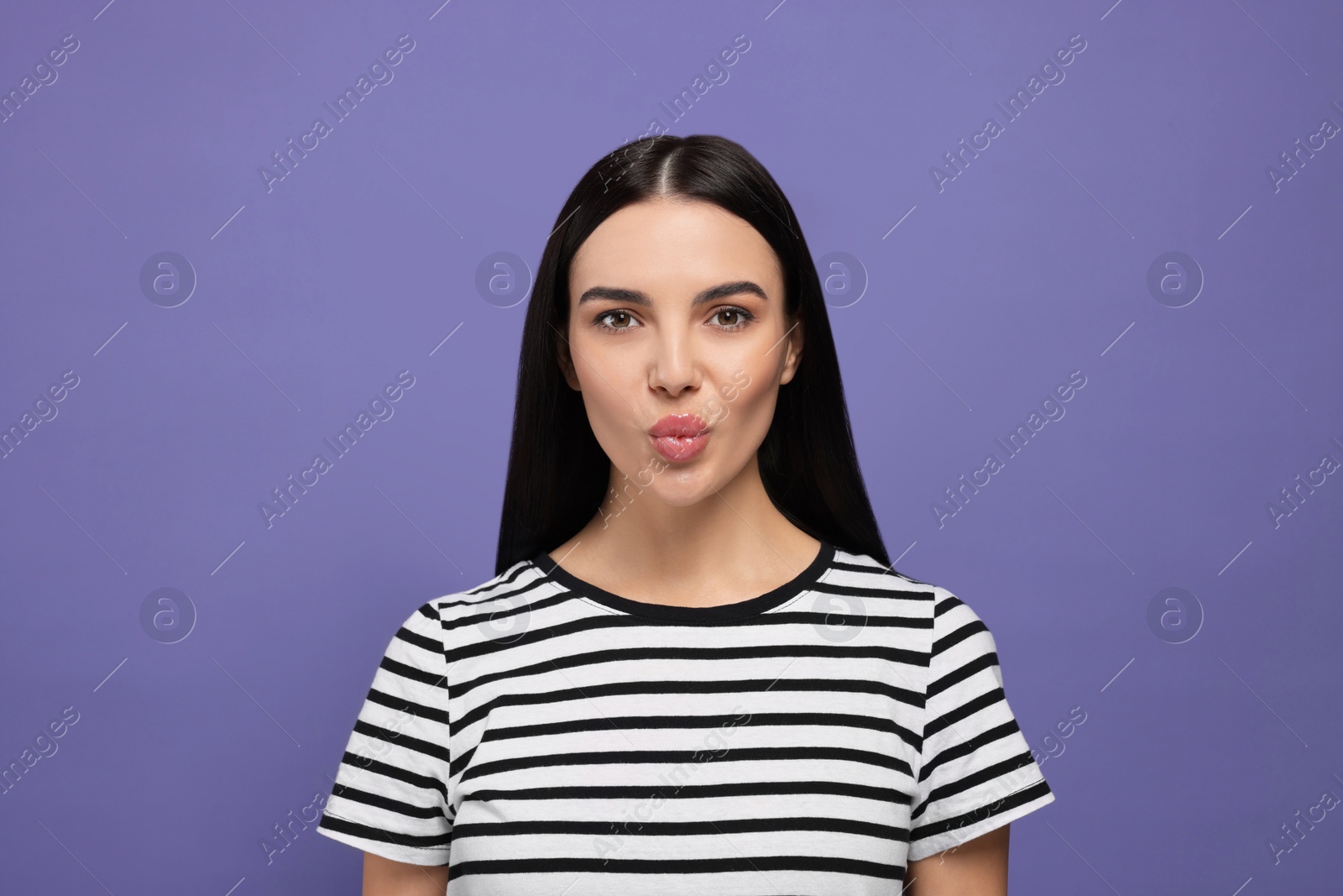 Photo of Beautiful young woman blowing kiss on purple background