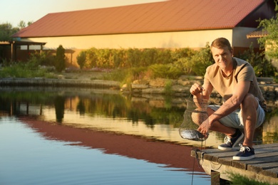 Man holding caught fish at lake on sunny day