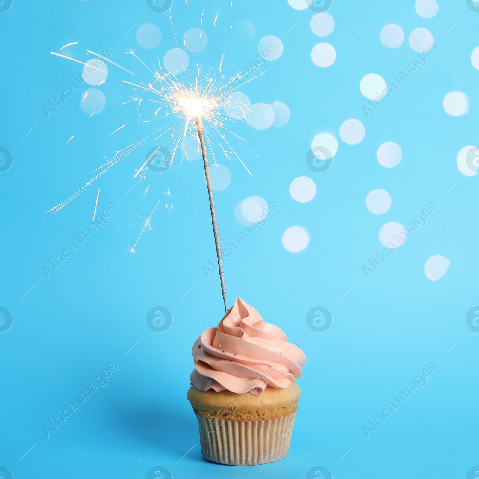 Image of Birthday cupcake with sparkler on light blue background