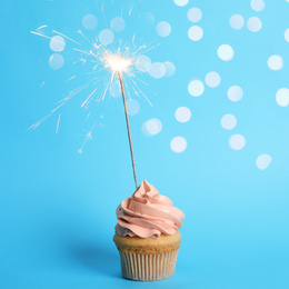 Birthday cupcake with sparkler on light blue background