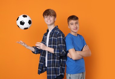 Photo of Happy teenage boys with soccer ball on orange background