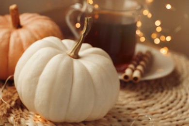 Photo of Pumpkins and hot drink on wicker mat indoors