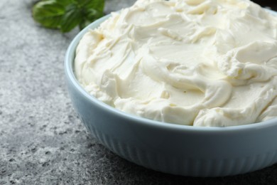 Photo of Bowl of tasty cream cheese on grey table, closeup