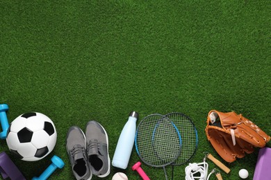 Photo of Different sports equipment on green grass, flat lay. Space for text