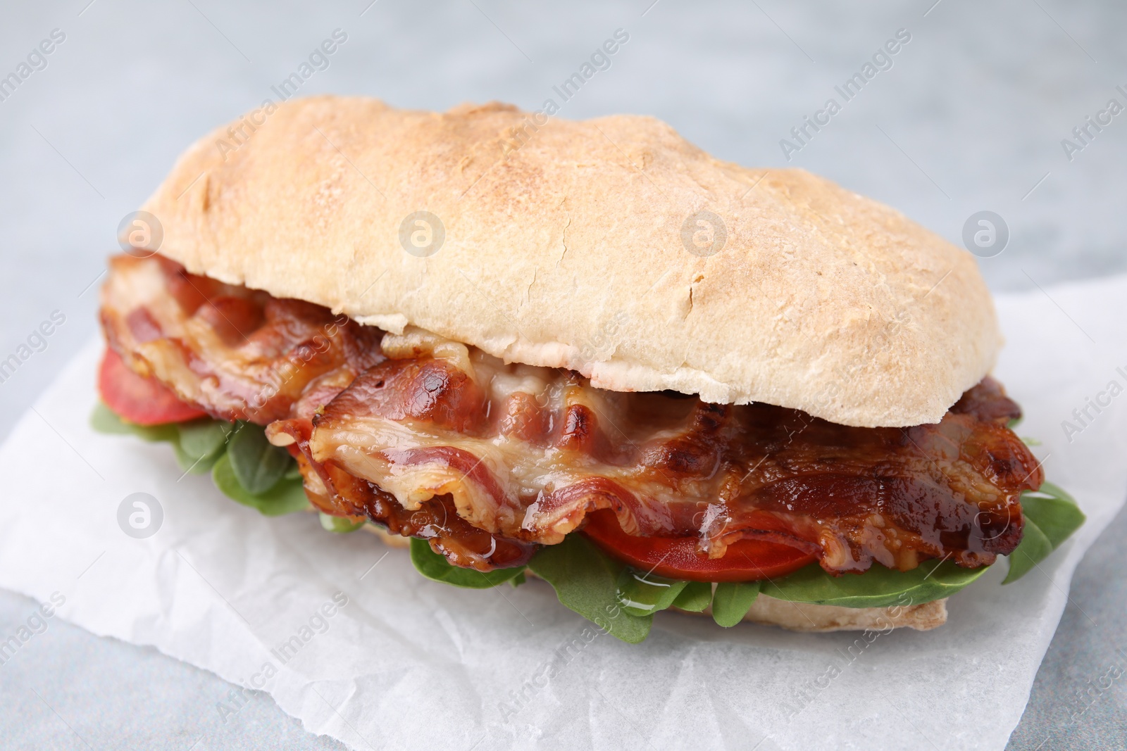 Photo of Tasty sandwich with bacon on grey table, closeup