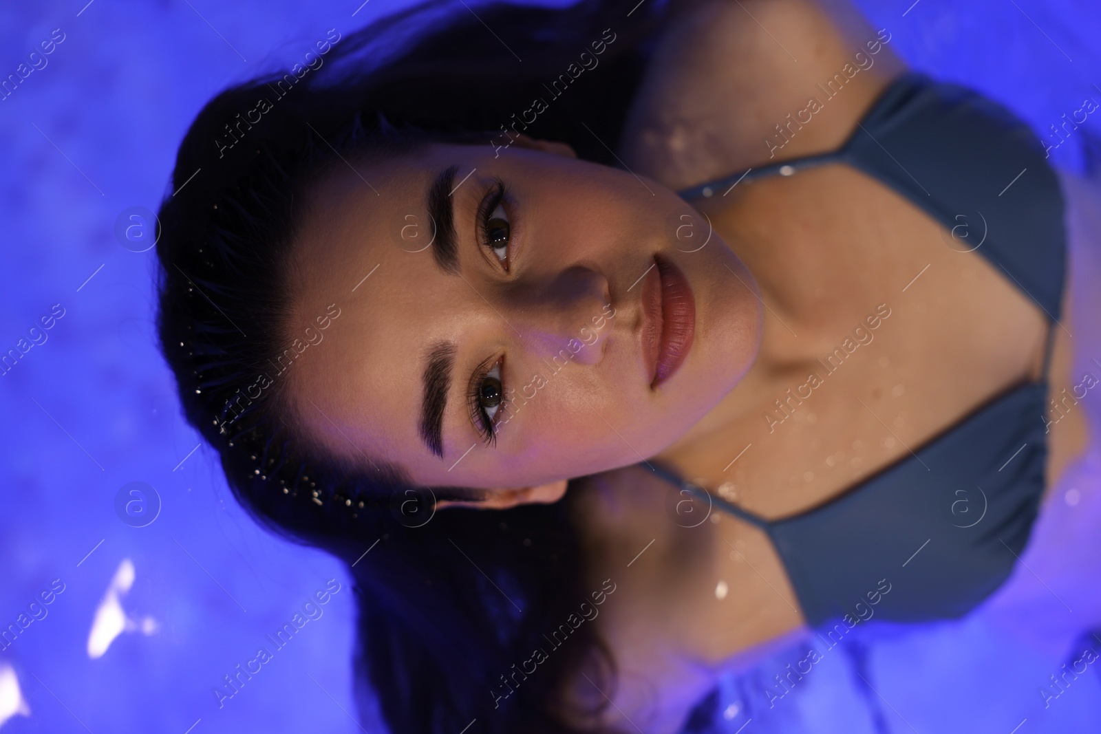 Photo of Beautiful woman relaxing in spa swimming pool, top view