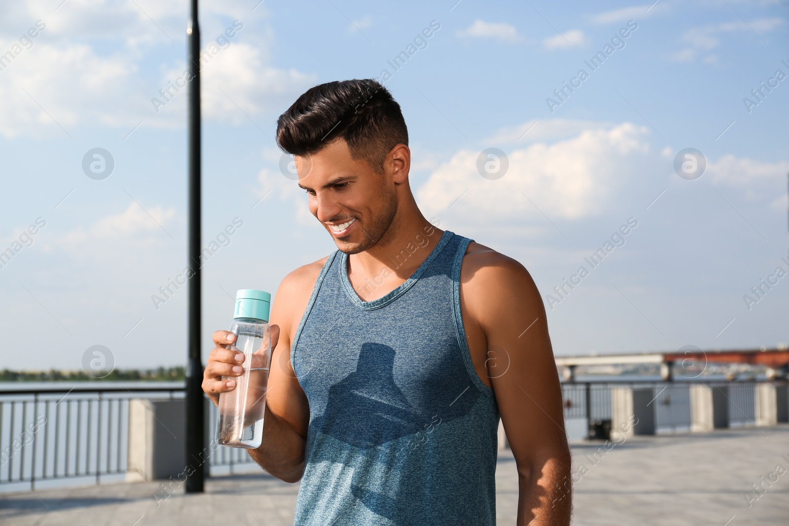Photo of Handsome man in sportswear with bottle of water outdoors on sunny day