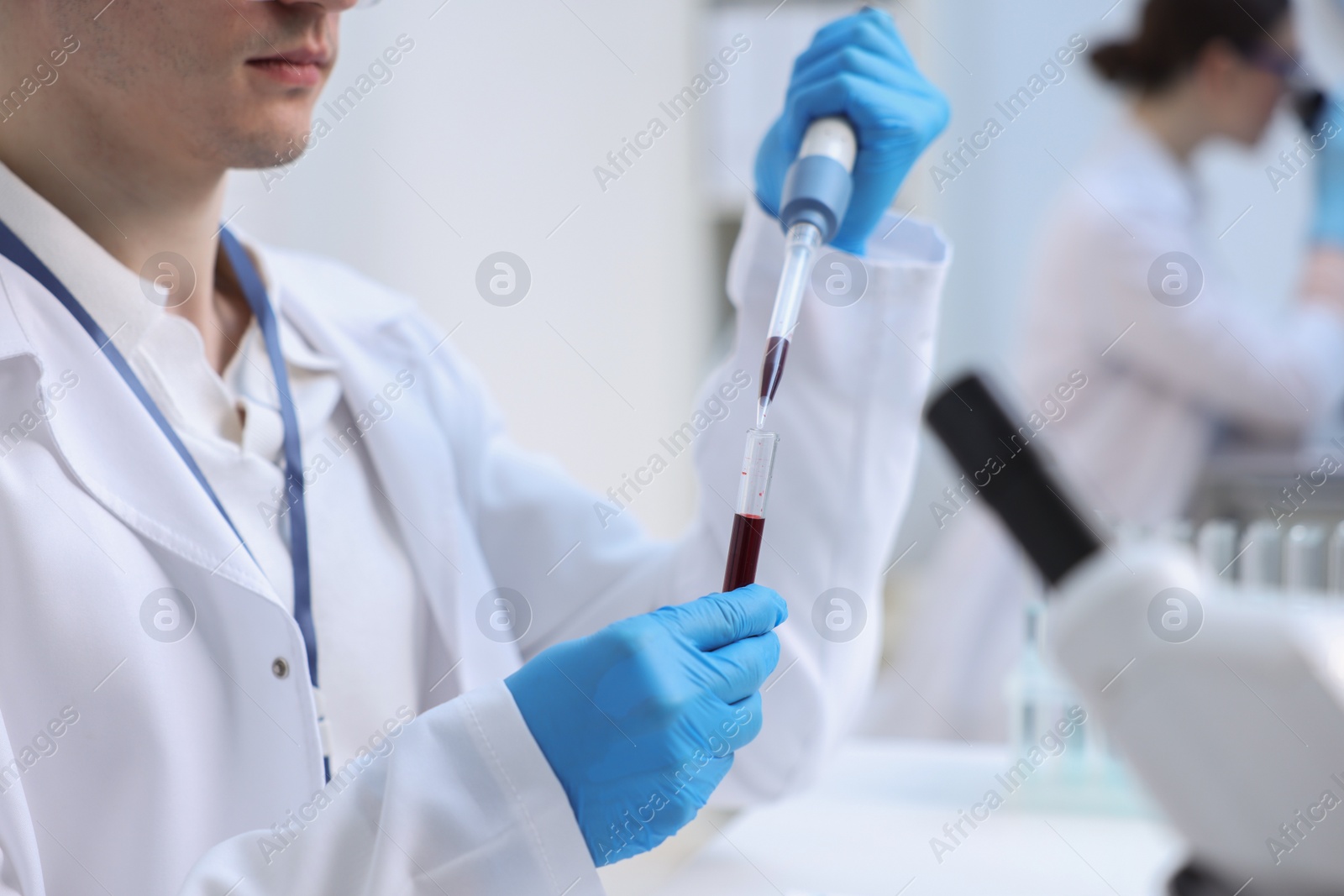 Photo of Scientist dripping sample into test tube in laboratory, closeup