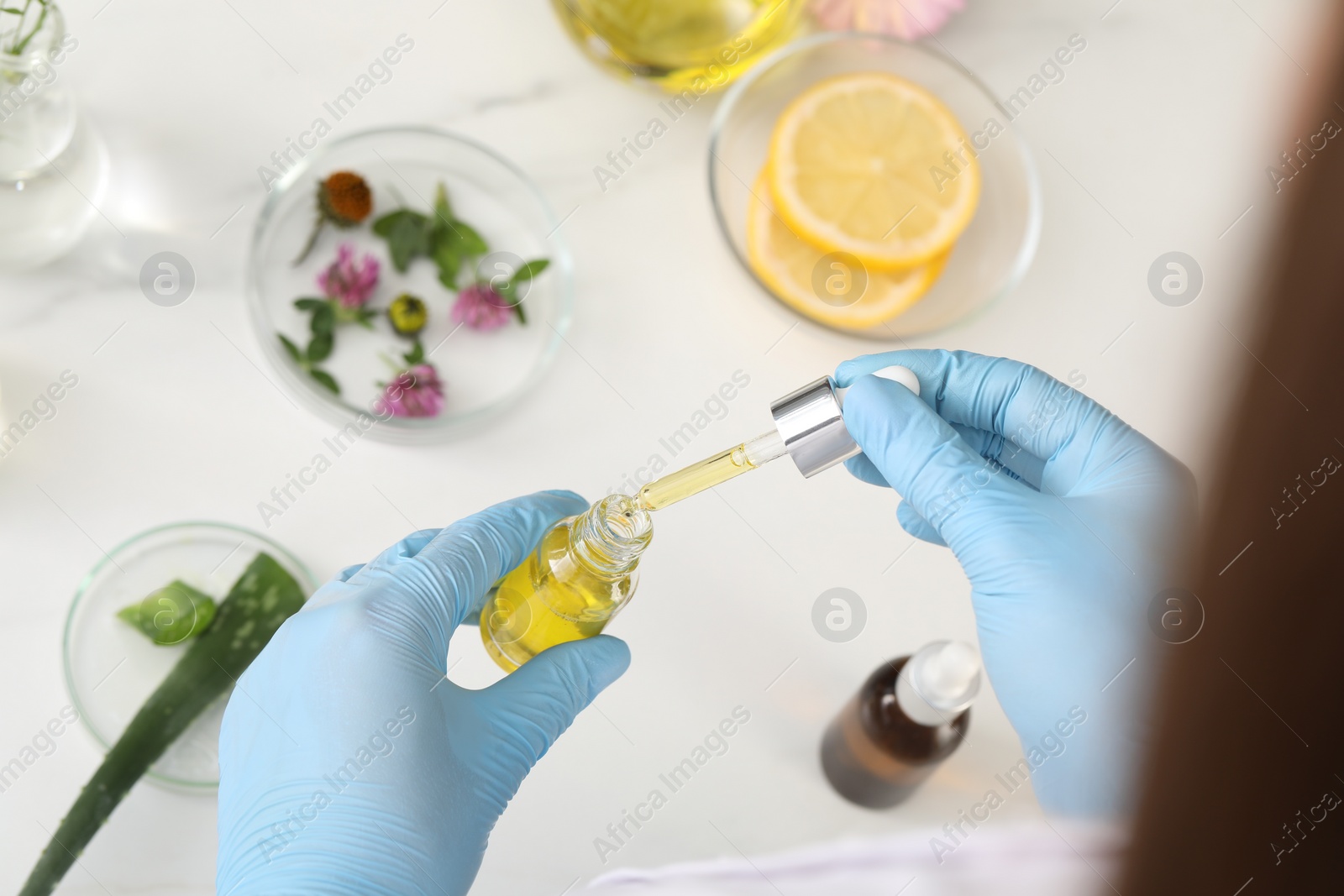 Photo of Scientist developing cosmetic oil at white table, above view