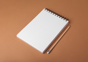 Photo of Open notebook and pencil on light brown background