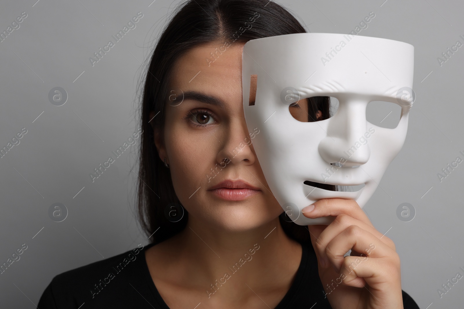 Photo of Multiple personality concept. Woman with mask on grey background