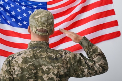 Soldier in uniform and United states of America flag on white background, back view