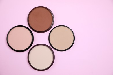 Photo of Different face powders on pink background, flat lay. Space for text