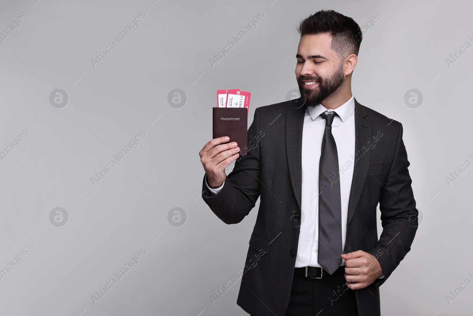 Photo of Happy businessman with passport and tickets on grey background. Space for text