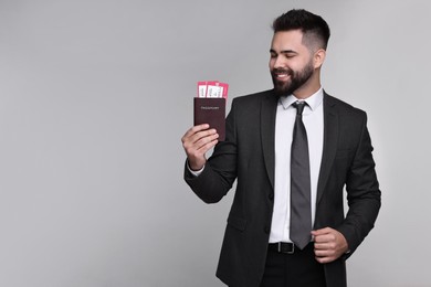 Photo of Happy businessman with passport and tickets on grey background. Space for text