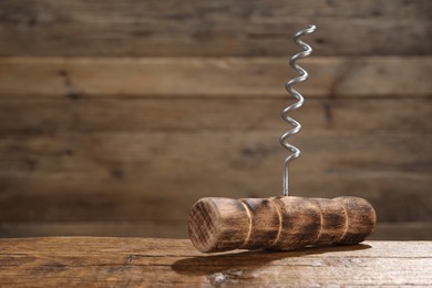 Photo of One corkscrew on wooden table, closeup. Space for text