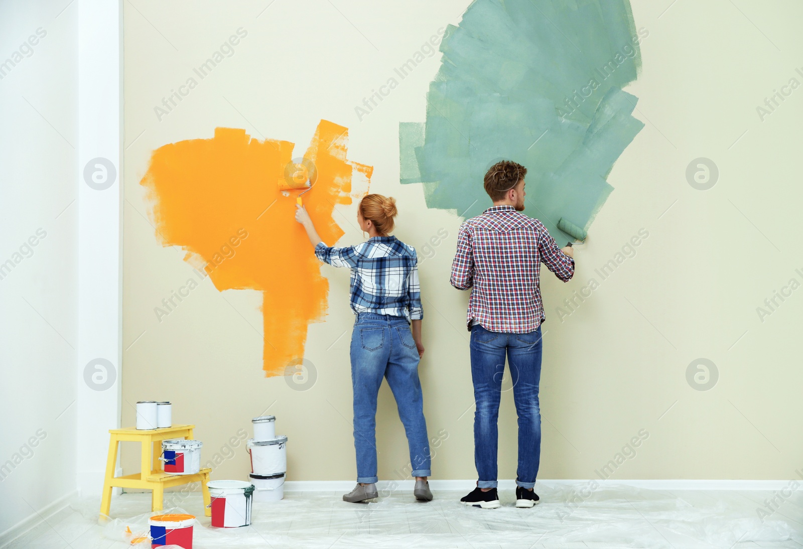 Photo of Young couple painting wall indoors. Home repair