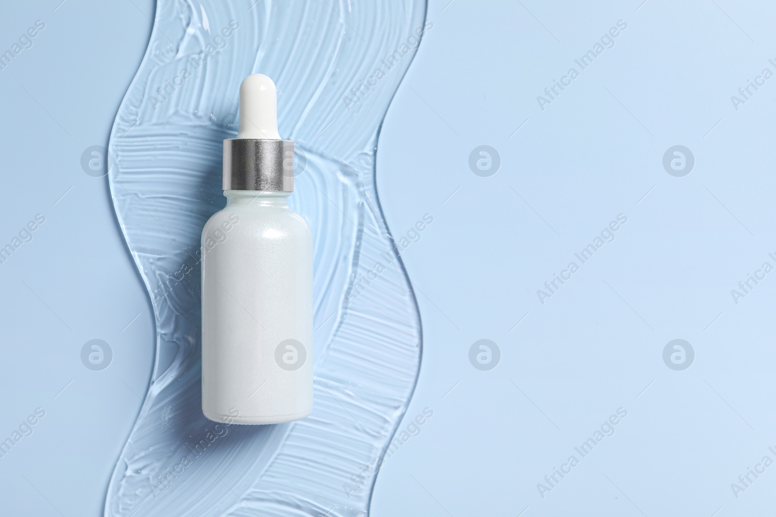 Photo of Bottle of cosmetic serum on light blue background, top view. Space for text