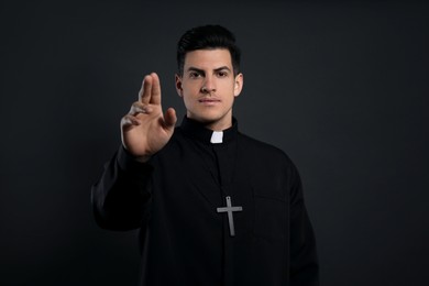Photo of Priest making blessing gesture on black background
