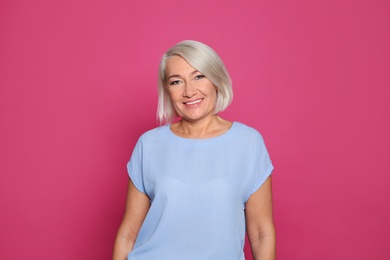 Photo of Portrait of mature woman laughing on color background