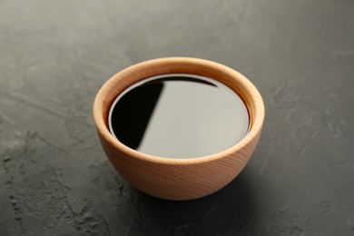 Photo of Soy sauce in wooden bowl on black textured table