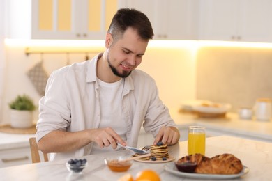 Smiling man having tasty breakfast at home