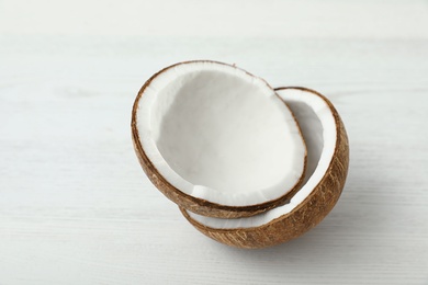 Photo of Halves of coconut on white wooden background
