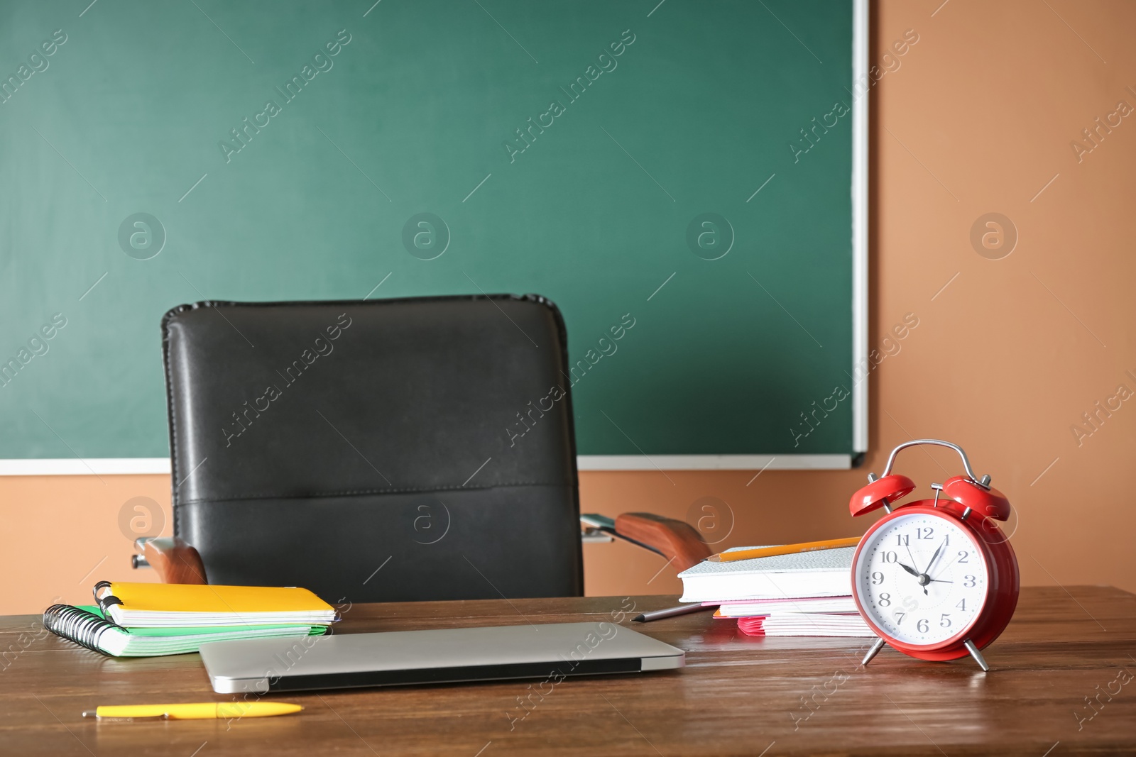 Photo of Laptop and alarm clock on table in classroom. Teacher day celebration