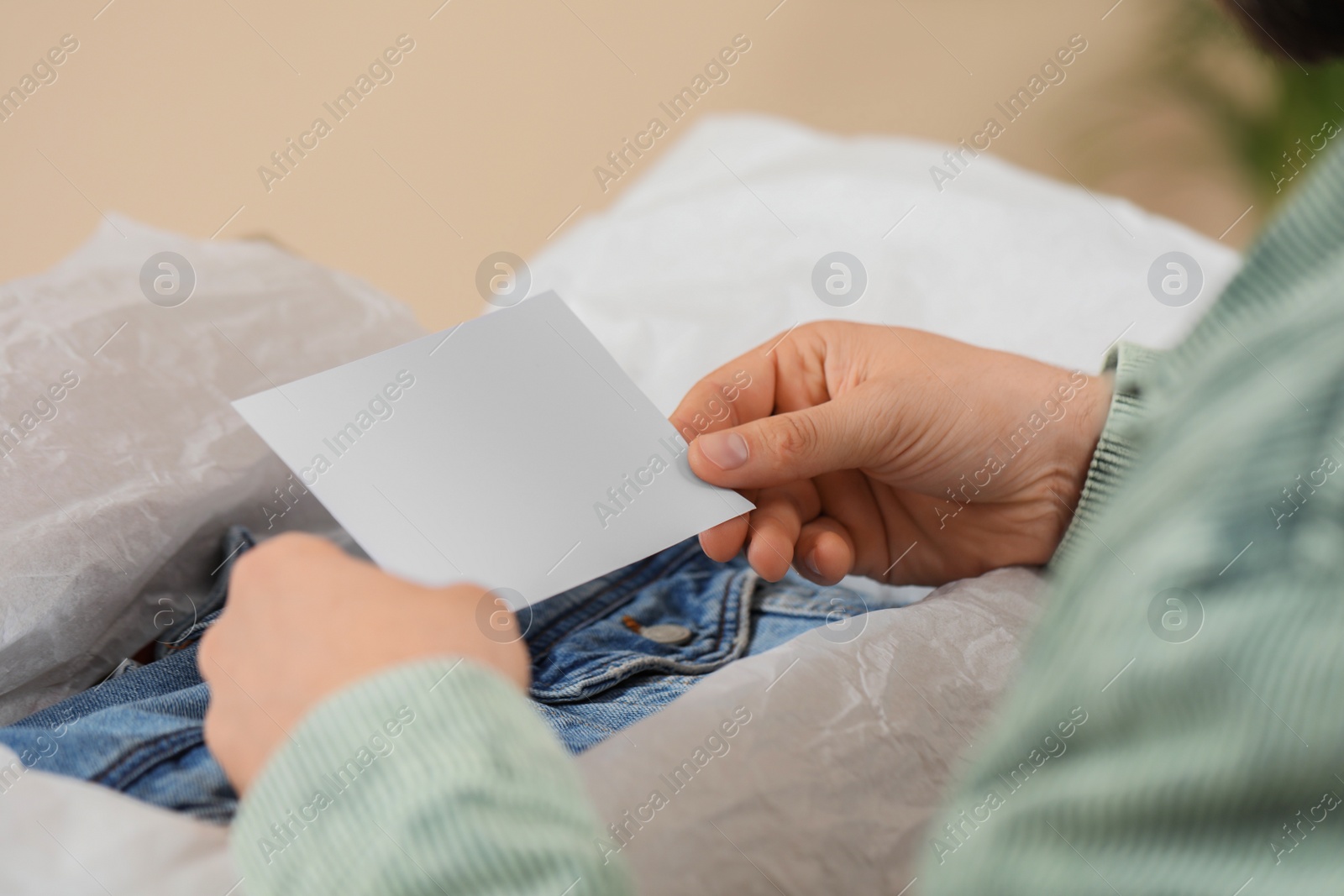 Photo of Man holding greeting card near parcel with Christmas gift, closeup