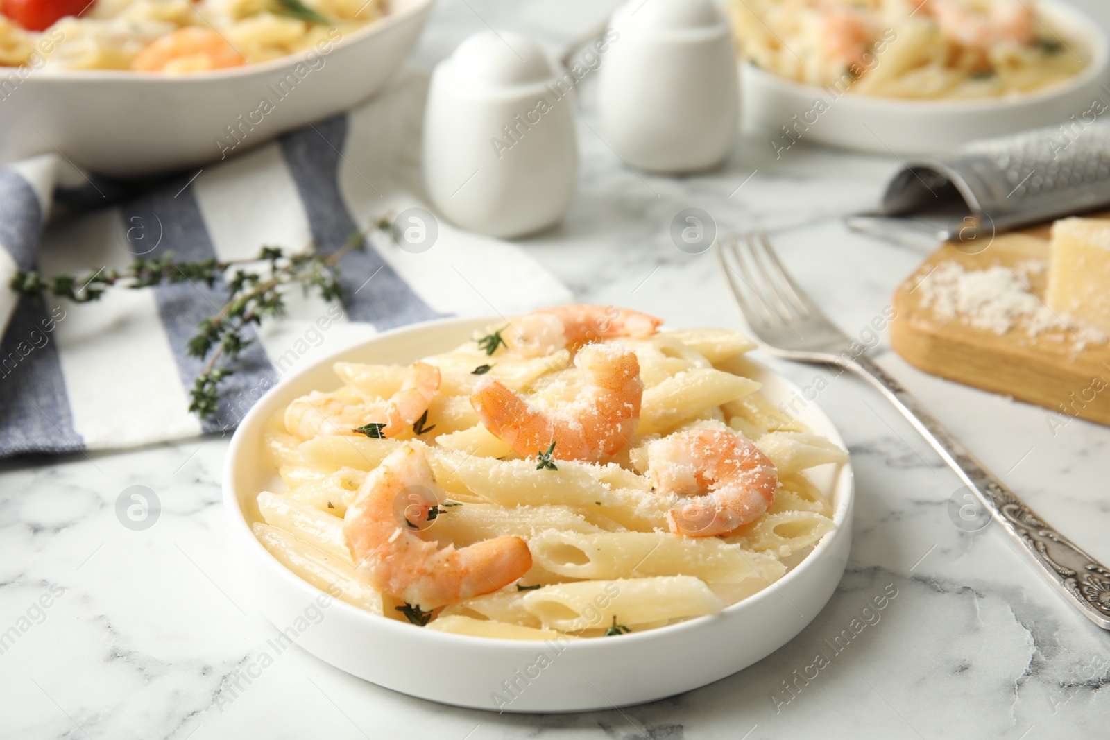 Photo of Delicious pasta with shrimps served on white marble table