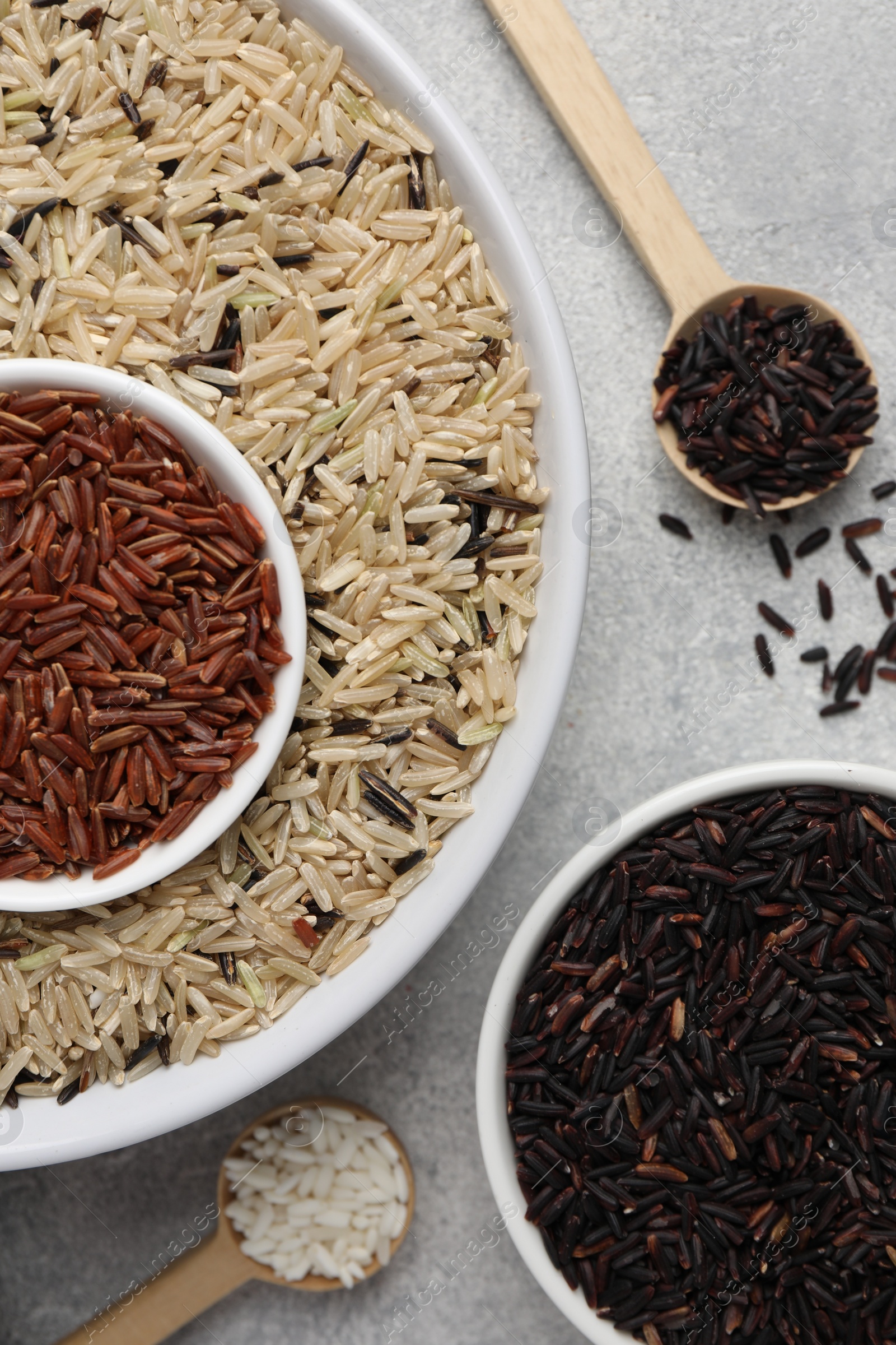 Photo of Different sorts of rice on grey table, flat lay